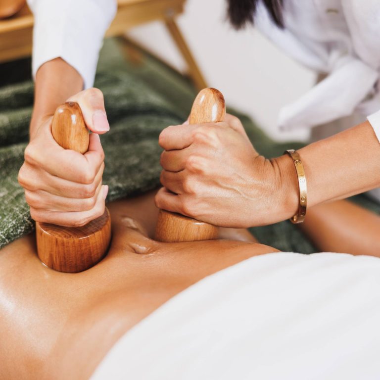 An unrecognizable woman getting anti cellulite maderotherapy massage with wooden cup at the beauty salon.